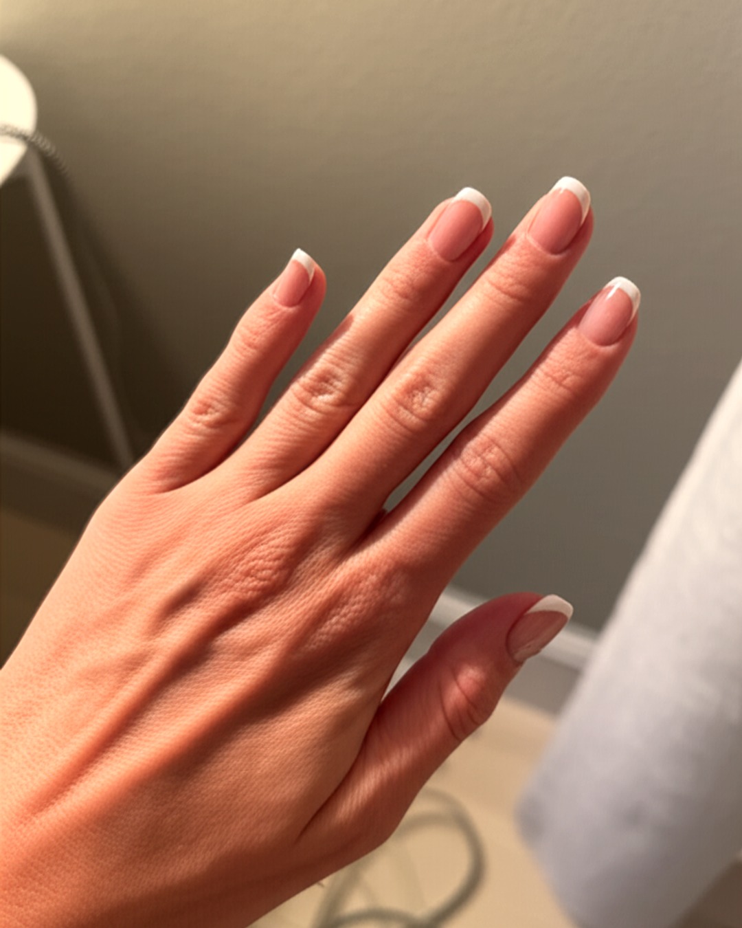 white french tip nails with natural base, almond shape, medium length, glossy finish